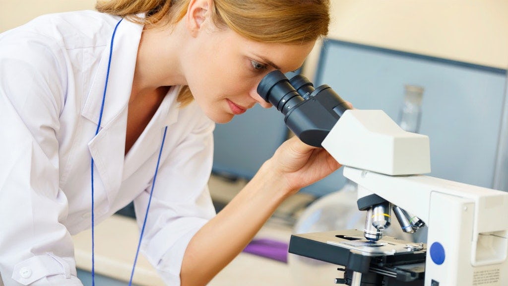 Medewerker kijkt in een microscoop