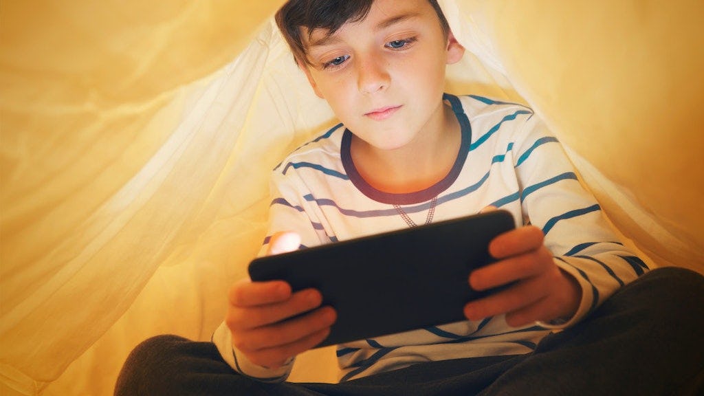 Kind onder de dekens op tablet